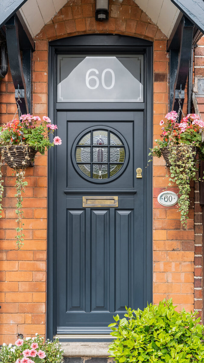 dark timber front door with a toplight and circular glass panel.
