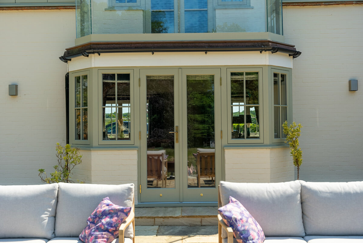 french doors and casement windows behind two outdoor sofas
