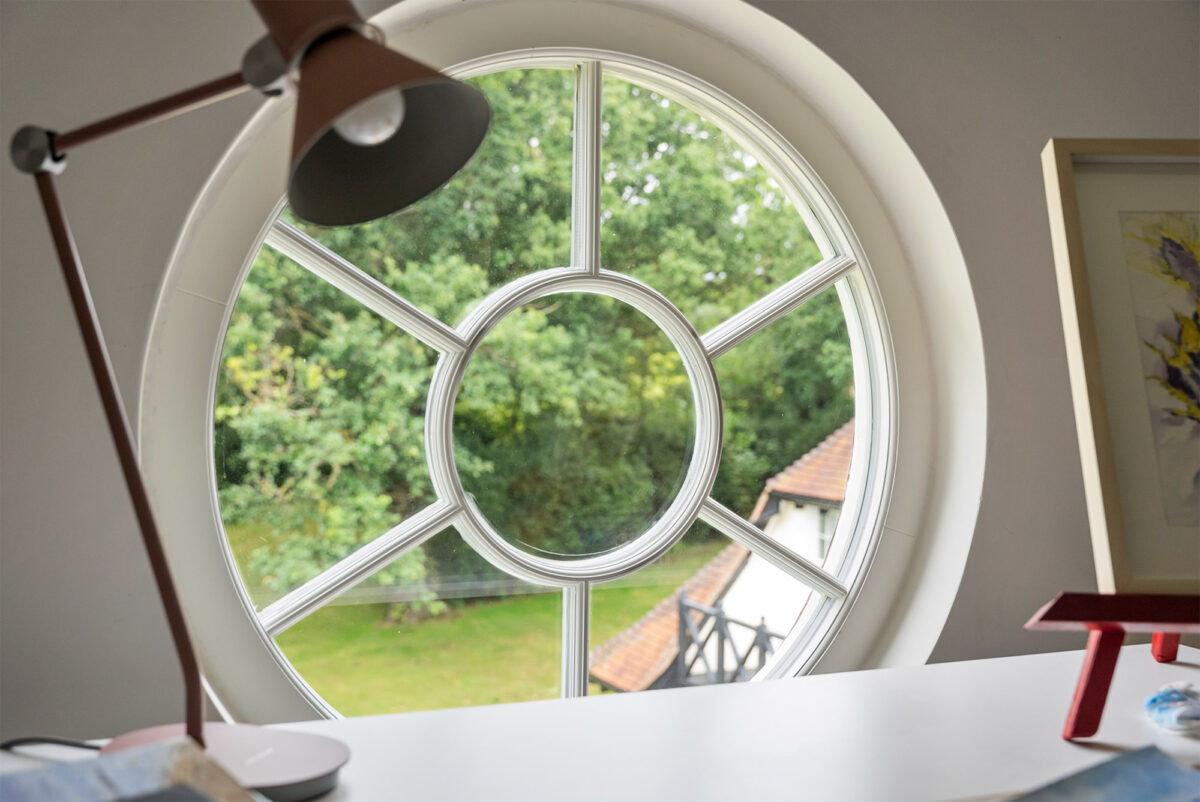 a circular casement window behind a desk