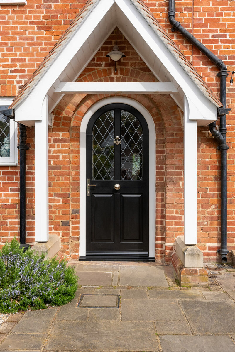 an arched black front door with leaded diamonds