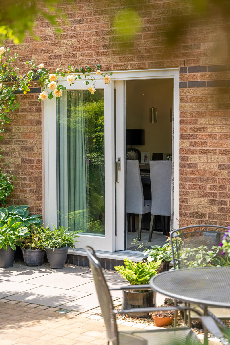 a set of sliding patio doors half open onto a garden with an outdoor table