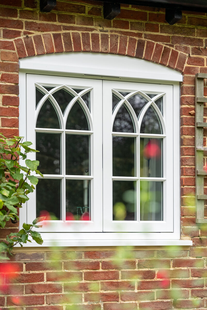 Flush casement windows finished in White, with 18mm astragal glazing bars in a gothic formation. Manufactured in Engineered European Redwood.