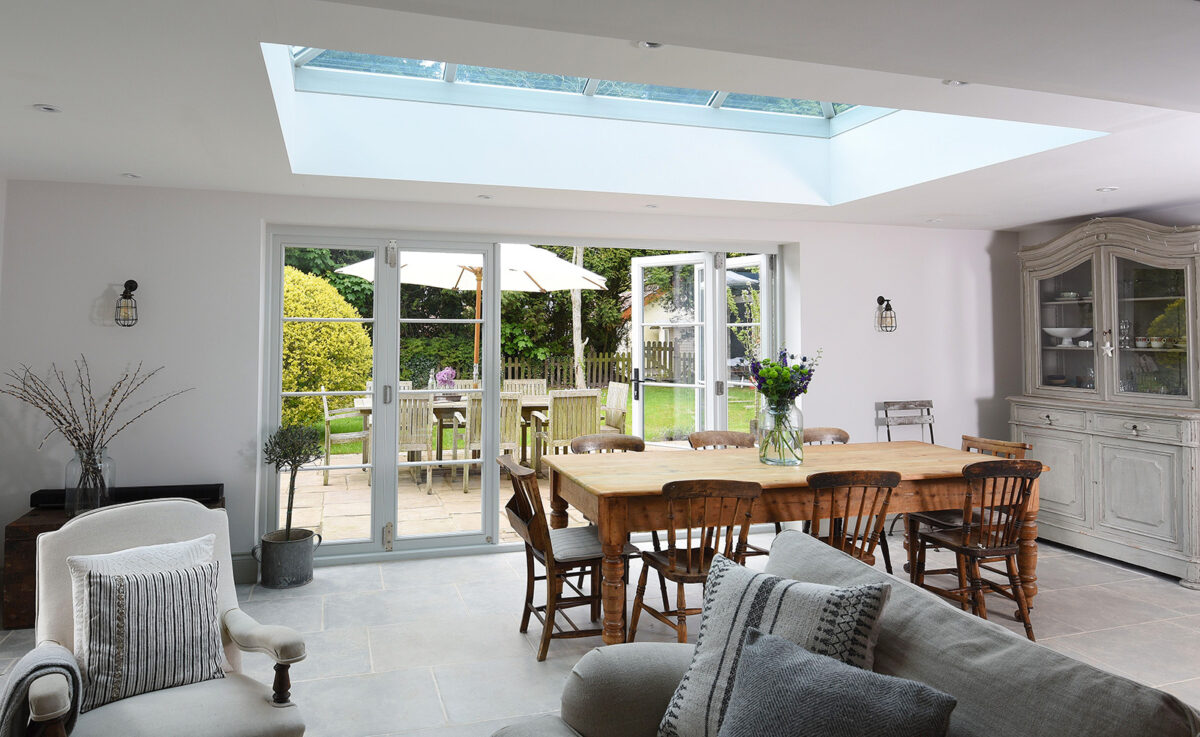 a sun room with a dining table and a partially open set of bifold doors behind
