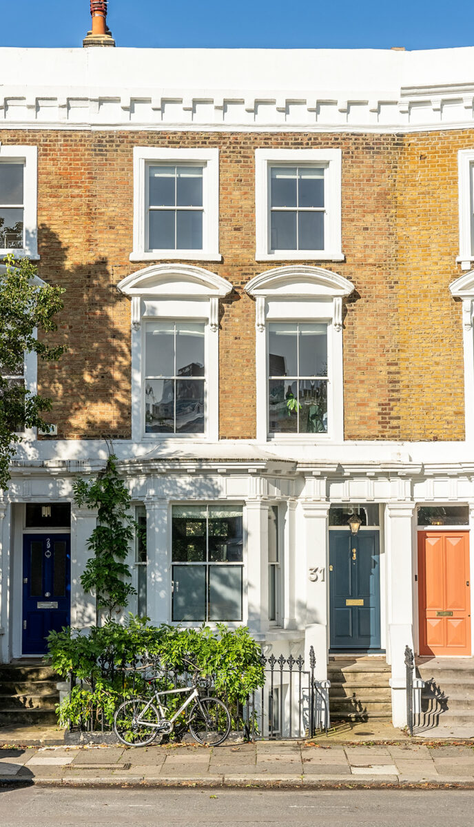 a three storey london townhouse with sash windows and a blue front door