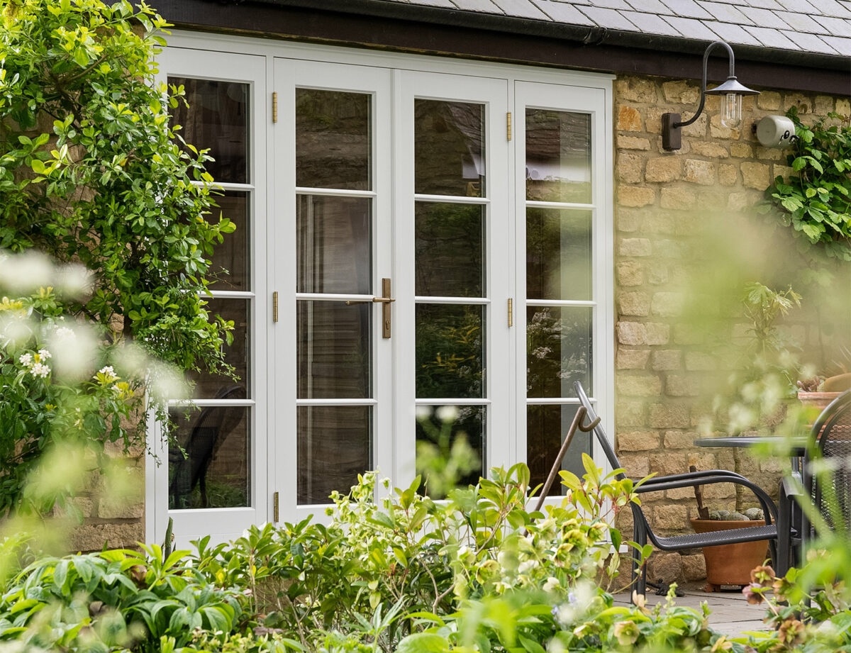 a white set of timber french doors surrounded by greenery