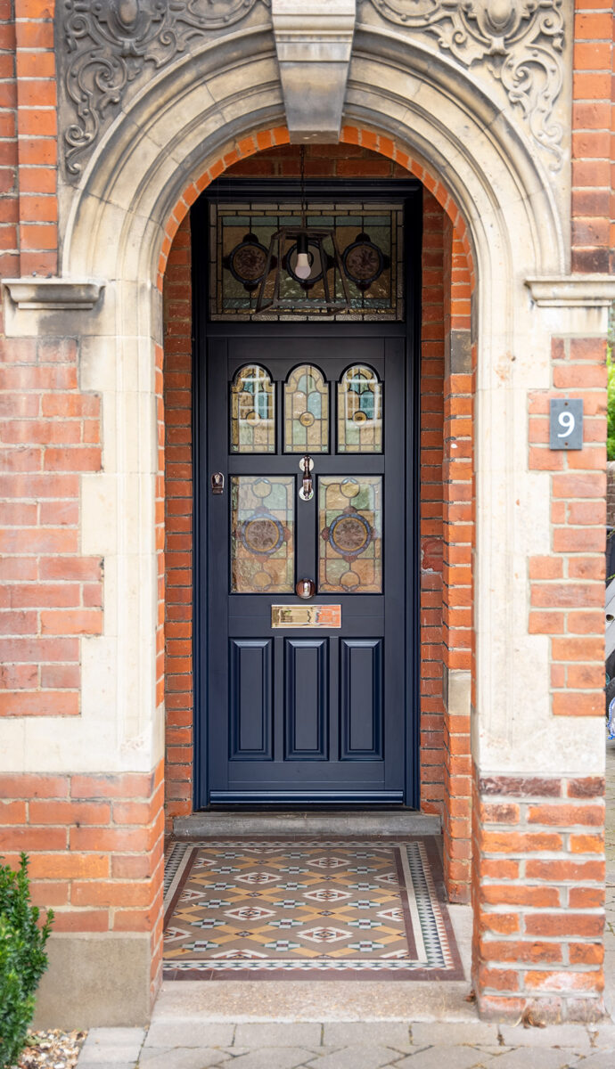 a dark front door with stained glass set within a stone archway