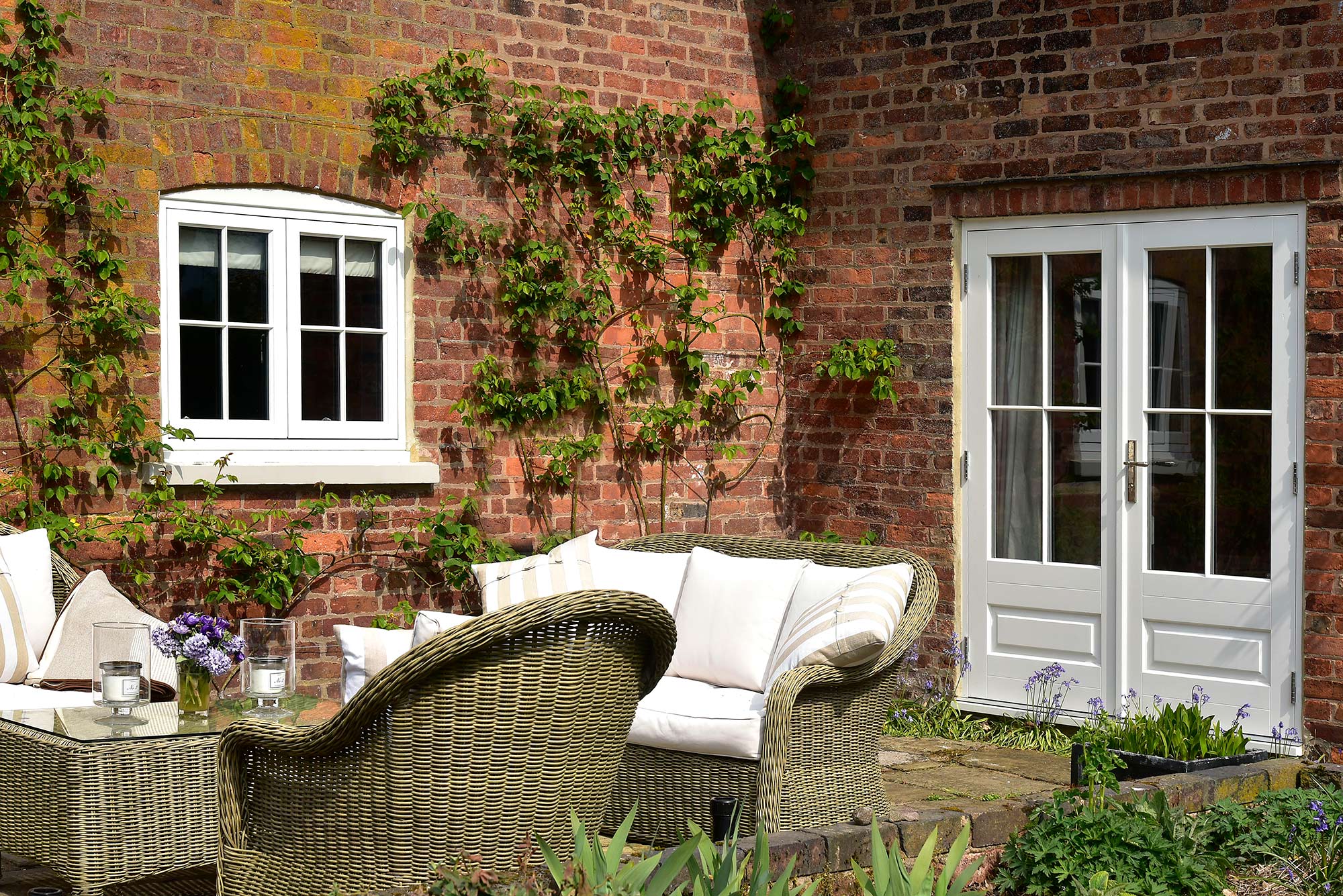 casement windows and french doors behind a patio seating area